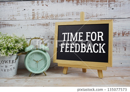 Time For Feedback text written on blackboard with alarm clock on wooden background 135077573