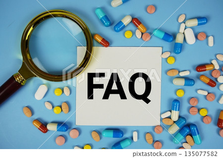FAQ with Various Colored Pills and magnifying glass on blue background 135077582
