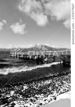「一月的支笏湖”，海浪拍打著冰封的碼頭，背景是白雪皚皚的惠庭山，黑白照片。 135077607