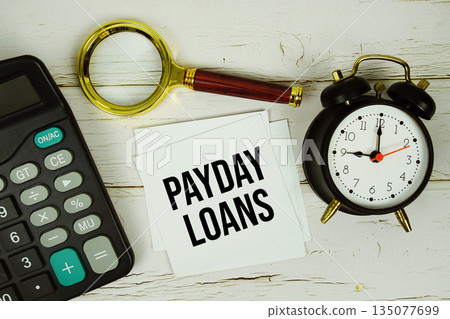 Payday Loans text with calculator, magnifying glass and alarm clock on wooden background Payday Loans text with calculator, magnifying glass and alarm clock on wooden background 135077699