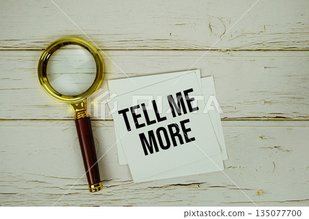Tell Me More text with magnifying glass on wooden background 135077700