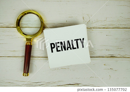 Penalty text with magnifying glass on wooden background 135077702