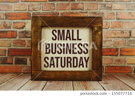 Small Business Saturday text written on wooden board standing with old brick wall background 135077718