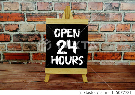 Open 24 Hours text written on wooden board standing with old brick wall background Open 24 Hours text written on wooden board standing with old brick wall background 135077721