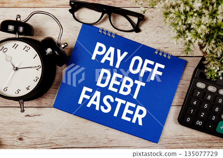 Pay Off Debt Faster text with alarm clock and calculator on wooden background 135077729