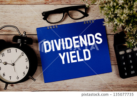 Dividends Yield text with alarm clock and calculator on wooden background Dividends Yield text with alarm clock and calculator on wooden background 135077735