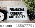 FCA Financial Conduct Authority text with alarm clock and calculator on wooden background 135077751