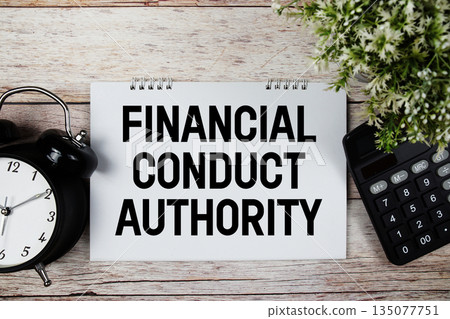 FCA Financial Conduct Authority text with alarm clock and calculator on wooden background 135077751