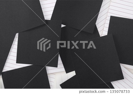 Black paper strewn over notepad Black paper strewn over notepad 135078733