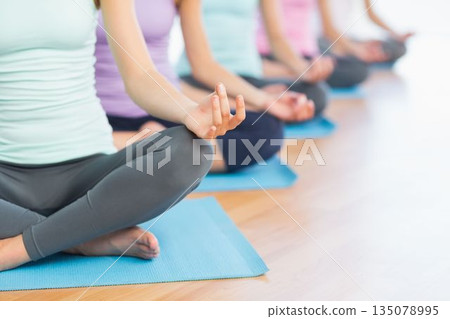 Five women are wearing pastel tops and practicing yoga cross-legged on blue mats in flat design Five women are wearing pastel tops and practicing yoga cross-legged on blue mats in flat design 135078995