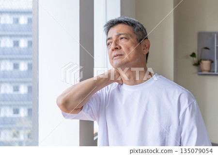 Senior man holding his neck by the window 135079054