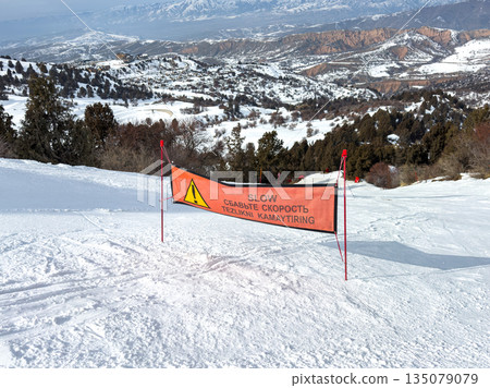 Orange slow sign on snowy ski slope at Amirsoy ski resort. 135079079