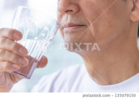 Senior men drinking water at the windowside Senior men drinking water at the windowside 135079150
