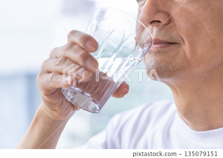 Senior men drinking water at the windowside 135079151