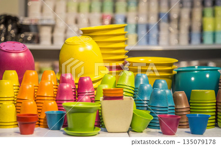 Assorted colorful plastic plant pots and flower containers stacked in a garden store. Vibrant gardening equipment and nursery supplies for home decor and planting Assorted colorful plastic plant pots and flower containers stacked in a garden store. Vibrant gardening equipment and nursery supplies for home decor and planting 135079178