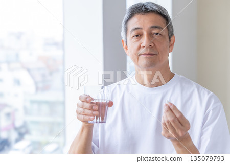 一位老人在窗邊吃藥 一位老人在窗邊吃藥 135079793