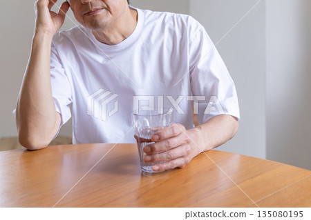 Senior man holding his head with water Senior man holding his head with water 135080195