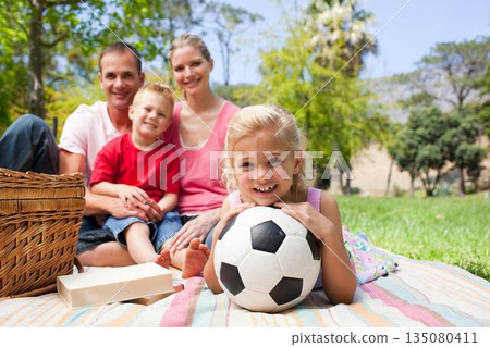 Little blond girl holding a soccer ball at a picnic 135080411