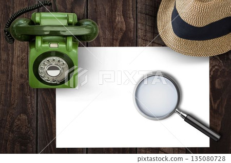 Magnifying glass on paper on side of brown hat and green phone 135080728