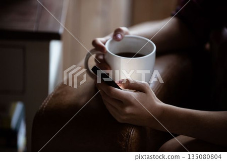 Mid section of woman using mobile phone while having coffee 135080804