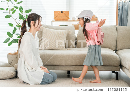 一位母親在家裡的客廳幫女兒穿衣服 135081135