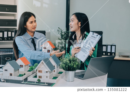 Professional real estate agents brainstorming house project while planning home investment with architectural model and documents 135081222