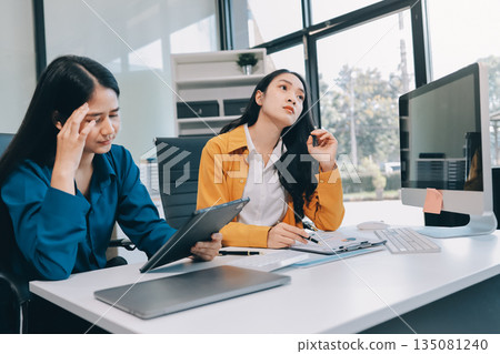 Asian women stressed at work. Teamwork in business with Older Asian women manager. Stressful deadline for young Asian women professional. 135081240