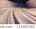 Tire tracks left on snowy roads. Gentle street lights shining on snowy roads late at night. 135081362