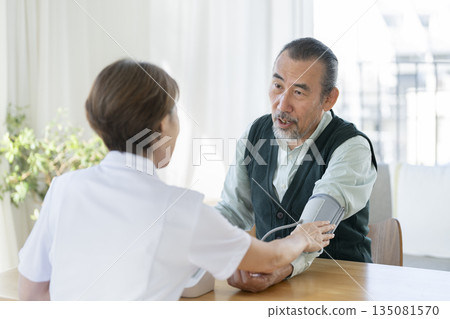 Senior man having his blood pressure measured by medical staff Senior man having his blood pressure measured by medical staff 135081570