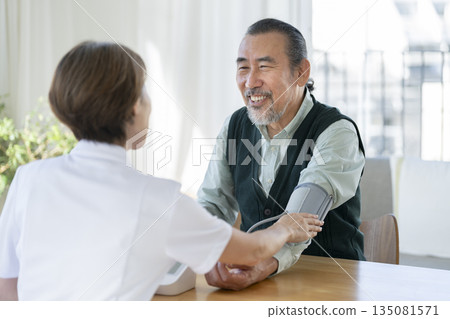 一名70多歲的男子正在接受醫護人員的血壓測量。 135081571