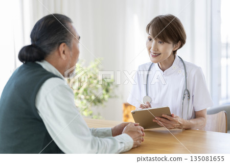 醫護人員正在用平板電腦聽一位老年男子說話。 醫護人員正在用平板電腦聽一位老年男子說話。 135081655