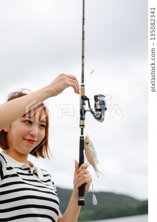 一位女士高興地看著自己釣到的魚。 (照片由沖繩海濱度假村雅提供) 一位女士高興地看著自己釣到的魚。 (照片由沖繩海濱度假村雅提供) 135082341