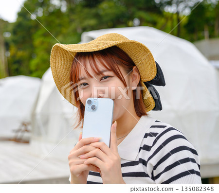 一位女士手持草帽和智慧型手機（照片由沖繩海濱度假村雅提供） 135082348
