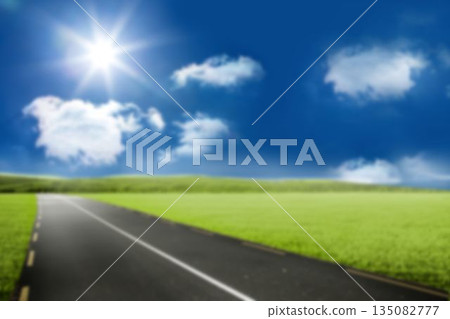 Road by grass field against blue sky 135082777
