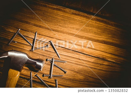 Claw hammer is resting on workbench plank in flat design, with scattered steel nails, copy space 135082832