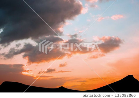 Flat design illustration showing rolling desert sand dune silhouettes under glowing sunset clouds Flat design illustration showing rolling desert sand dune silhouettes under glowing sunset clouds 135082866
