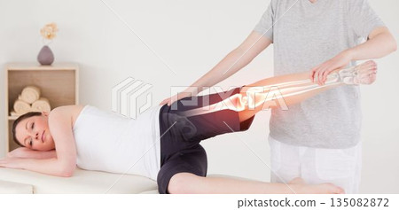 Injured woman relaxing on bed while having leg massage 135082872