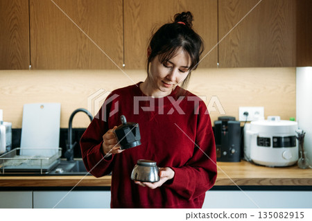 Person assembles components of moka pot in kitchen. Handcrafted coffee, manual espresso technique, specialty coffee ritual, coffee brewing steps. Person assembles components of moka pot in kitchen. Handcrafted coffee, manual espresso technique, specialty coffee ritual, coffee brewing steps. 135082915