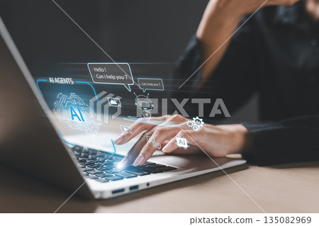 Close-up of hands typing on laptop with AI chatbot interface, virtual assistant icons, representing artificial intelligence technology, machine learning and digital communication. 135082969