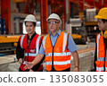 Three industrial engineers wearing safety uniform walk and discuss operations inside heavy factory, representing leadership, teamwork, and communication in high-risk industrial. 135083055