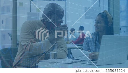 Discussing senior man and woman reviewing documents at office table with data charts overlay 135083224