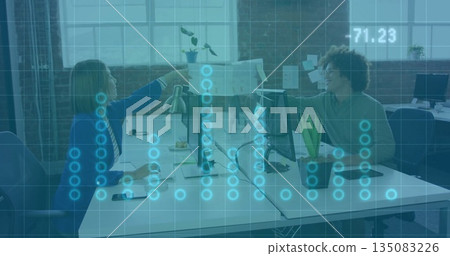 Handing printed document across shared desk in open office, woman wearing blue blazer with monitors Handing printed document across shared desk in open office, woman wearing blue blazer with monitors 135083226