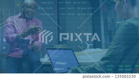 Gesturing senior man holding notepad in conference room, with laptop and turbine model, copy space 135083230