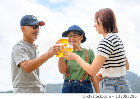 Three generations toasting with beer outdoors [Photography cooperation: Oki Seaside Resort Miyabi] 135083296