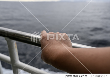 Hands holding the railing of a boat Hands holding the railing of a boat 135083313
