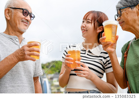三代人在戶外舉杯暢飲啤酒 [攝影協助：沖繩海濱度假村雅] 135083325