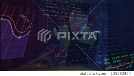 Korean man viewing stock graphs on glass panel in server room, with safety vest, red headphones 135083464
