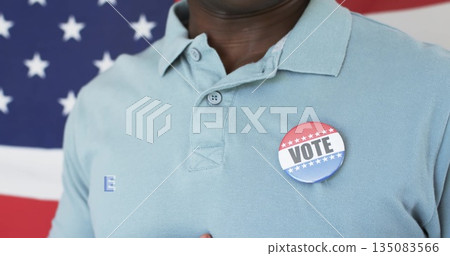 Displaying man wearing light blue polo shirt at campaign event, with VOTE button and flag backdrop Displaying man wearing light blue polo shirt at campaign event, with VOTE button and flag backdrop 135083566