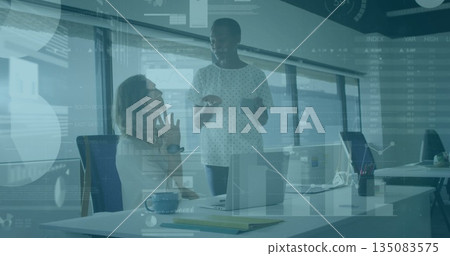 Analyzing data charts, two female colleagues collaborating at office desk with laptop and tablet Analyzing data charts, two female colleagues collaborating at office desk with laptop and tablet 135083575