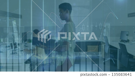 Reading colleague wearing fitted sweater and slacks in office, holding binder with financial charts 135083641